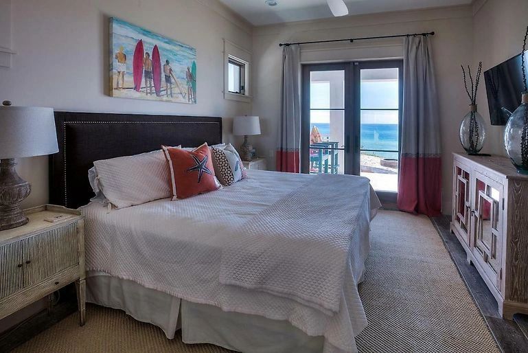Coastal bedroom with black upholstered bed and ocean balcony